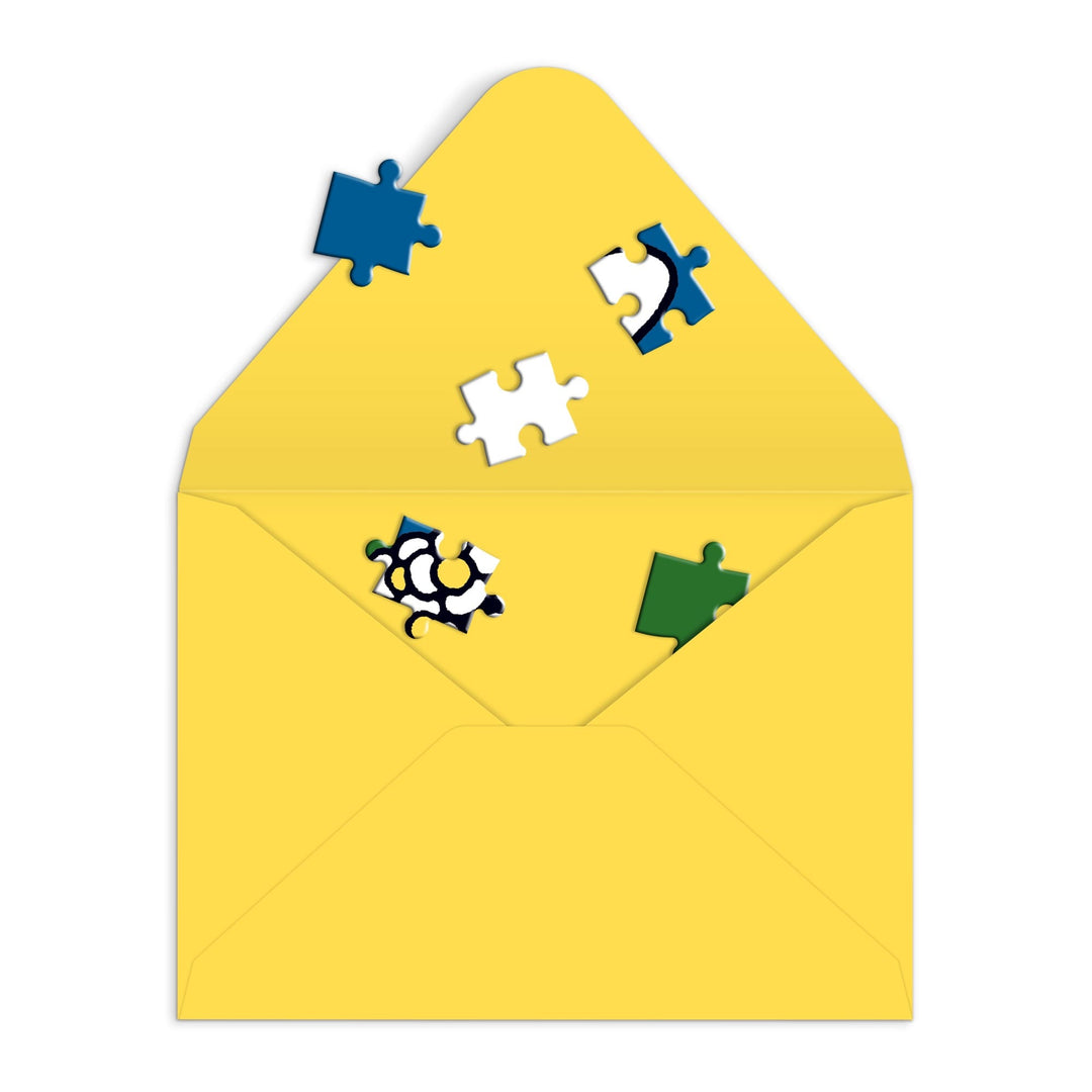 A Miffy with Flowers Greeting Card Puzzle by Miffy features a yellow open envelope with colorful jigsaw pieces scattered inside and around it, all on a white background.