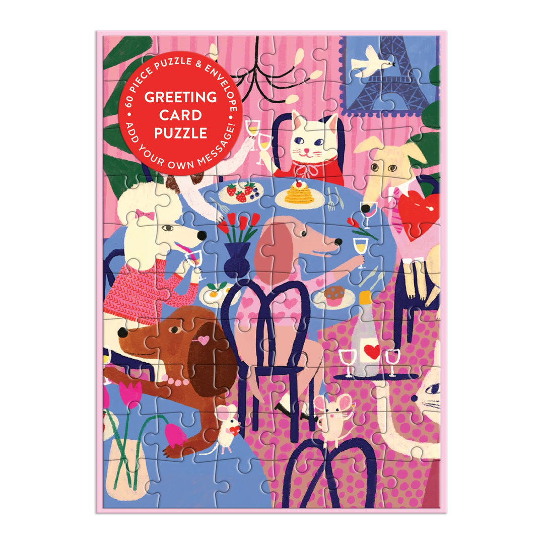 Colorful cats and dogs gather around a flower-adorned table on a pink and purple background in the completed Anne Bentley Paws for Love Greeting Card Puzzle.
