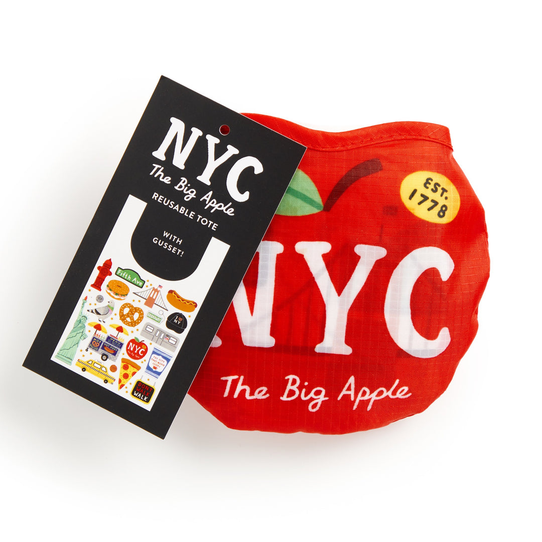The Holly Maguire Big Apple Packable Nylon Tote Bag is a lightweight, water-resistant tote that folds into a red apple shape with NYC The Big Apple printed on it. A tag displays New York icons and indicates the totes design.