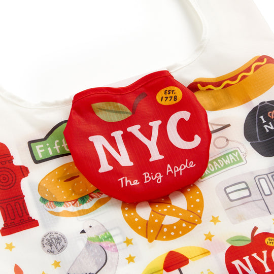 The Big Apple Packable Nylon Tote Bag by Holly Maguire is a reusable, lightweight, water-resistant nylon tote featuring colorful NYC icons. It folds into a red apple-shaped pouch labeled NYC The Big Apple.