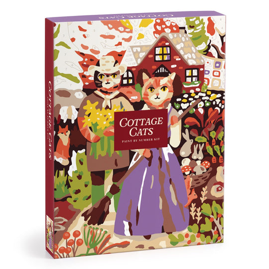 The Cottage Cats 9 x 12 Paint by Number Kit by Anja Riebensahm features two cats in traditional clothes standing before a cozy cottage, surrounded by colorful plants and flowers on the box illustration.