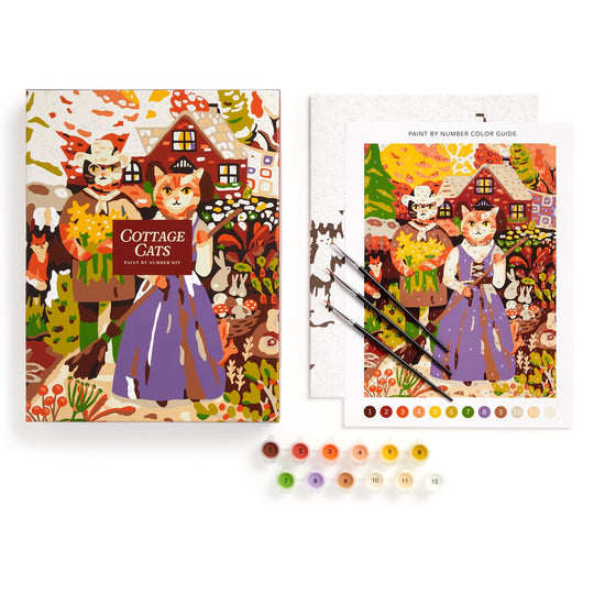 The Cottage Cats 9 x 12 Paint by Number Kit by Anja Riebensahm features a colorful box, a painting of three cats in dresses outside a cottage, three paintbrushes, a color guide, and 12 paint pots arranged in a row.