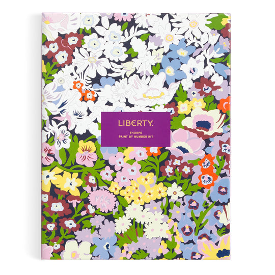 A vibrant Liberty London 9 x 12 Paint by Number Kit featuring the Thorpe pattern with lively floral designs in white, purple, red, and orange. The box has a central purple label reading “Liberty Thorpe Paint by Number Kit.”.