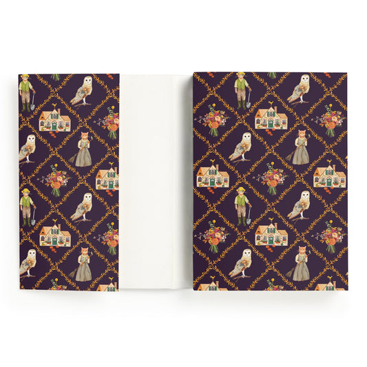 The Cottage Cats A5 Premium Notebook by Anja Riebensahm features a dark purple cover with white owls, dressed-up cats, flowers, houses, and vintage-clad children in gold diamond frames. The inside cover is plain white.