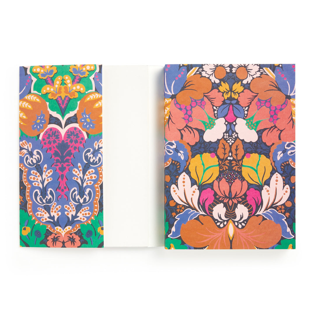 The Liberty Glastonbury Premium A5 Notebook by Liberty London features colorful, symmetrical floral and leaf patterns on the covers, inspired by classic Glastonbury designs, with premium paper stock and a vibrant inside cover.