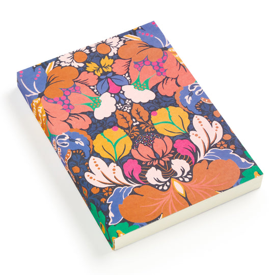 The Liberty London Liberty Glastonbury Premium A5 Notebook is shown closed, featuring a vibrant multicolored floral and leaf pattern cover, viewed at a slight angle against a white background.