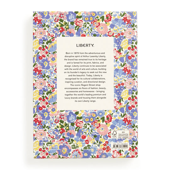 The image shows the back cover of the Liberty Nell, Annie and May Premium A5 Notebook by Liberty London, featuring a vibrant floral pattern. A central white box details Libertys heritage and reputation for prints and design.
