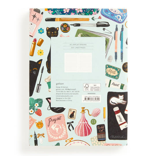 The Christine De Carvalho Purrfect Accessories Premium A5 Notebook features a vibrant cover with cats, perfume bottles, plants, makeup items, and chic stationery. A central white label displays the product details.