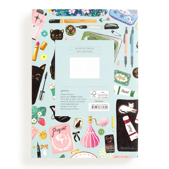 The Christine De Carvalho Purrfect Accessories Premium A5 Notebook features a colorful cat stationery cover with makeup, perfume, paint tubes, scissors, and more. Includes barcode and product info label on the back.