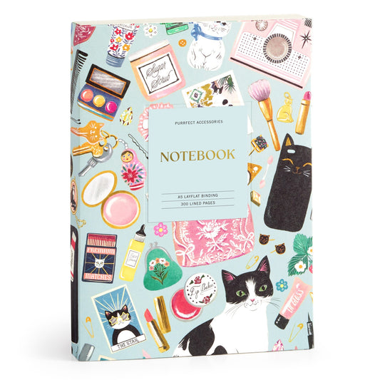 The Christine De Carvalho Purrfect Accessories Premium A5 Notebook features a colorful cover with cats, makeup, perfume bottles, and accessories on light blue, plus 300 lined premium pages.