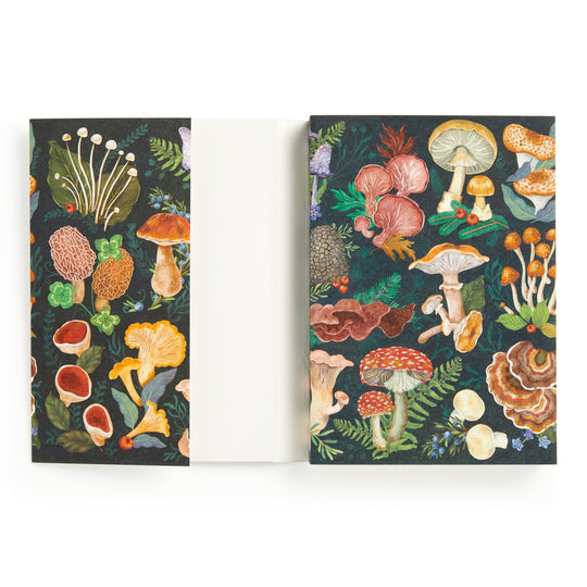The World of Mushrooms Premium A5 Notebook by Olga Akbarova features a colorful illustrated cover with mushrooms, ferns, and foliage on a dark background plus flaps—shown open to reveal blank pages—perfect as a botanical journal.