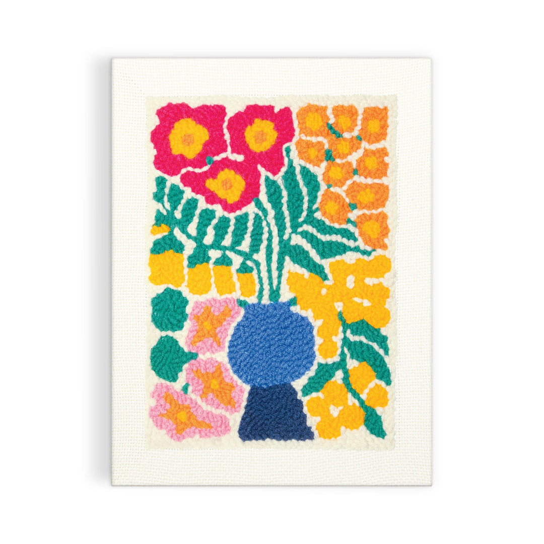 The Blooming Wildflowers Punch Needle Kit by Liv Lee features a vibrant blue vase with red, orange, and yellow flowers and green leaves, all crafted using punch needle embroidery on white canvas.