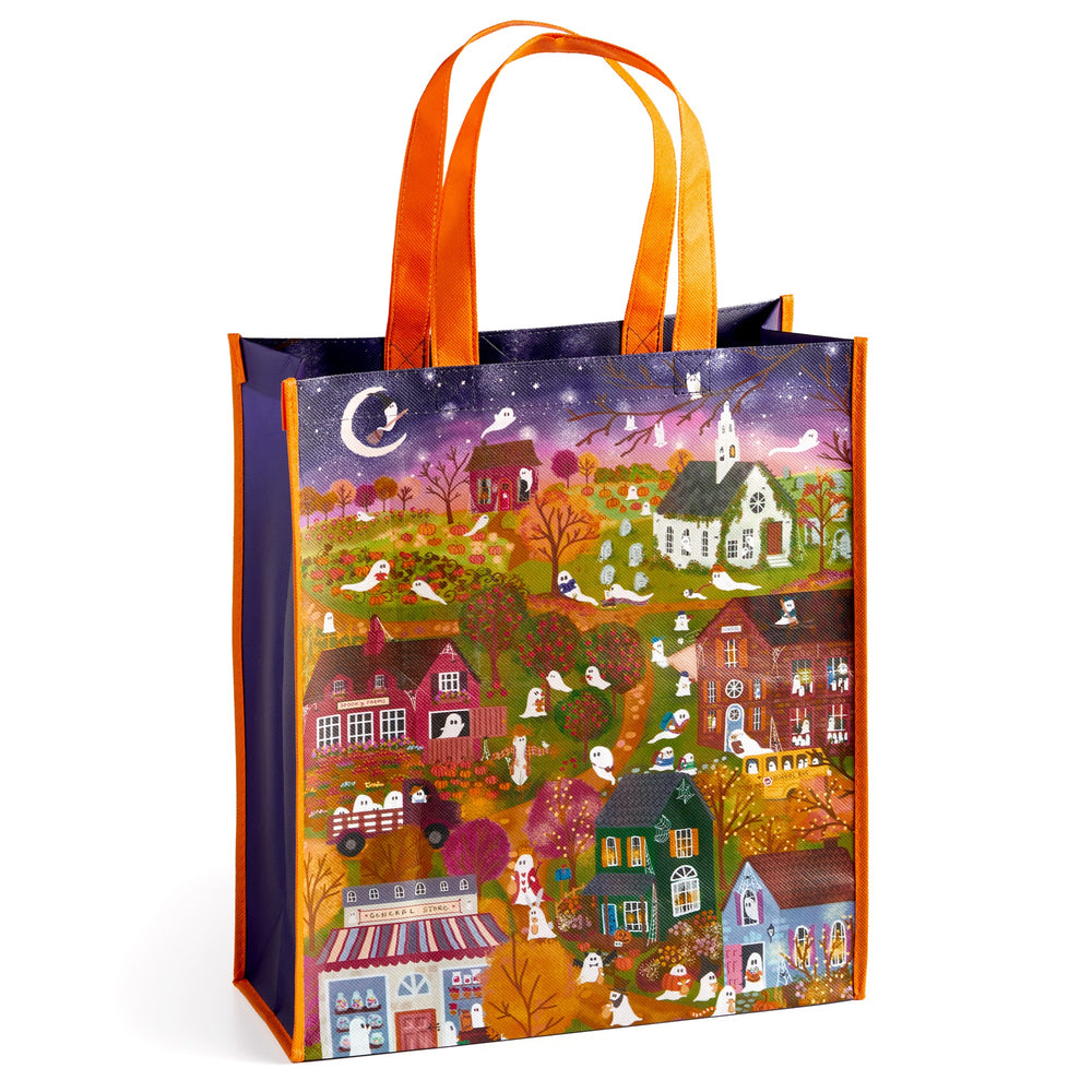 The Joy Laforme Spooky Village Reusable Shopping Bag features a whimsical Halloween scene with houses, trees, ghosts, pumpkins, and a crescent moon—perfect for eco-conscious shoppers.