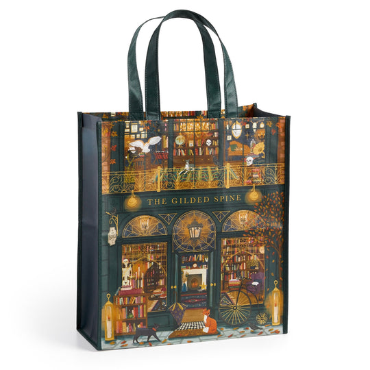 The Sally Wilson Gilded Spine Reusable Shopping Bag features dark green handles and an illustrated cozy bookstore scene with books, shelves, animals, and people, showcasing a storefront labeled The Gilded Spine.