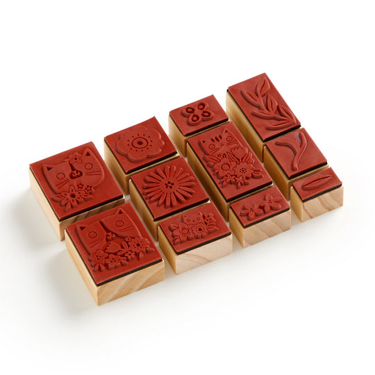 The Blooming Cats Rubber Stamp Set by Tara Lilly includes nine wood-mounted stamps with cat and botanical designs, such as flowers and leaves, arranged in three rows on a white background.