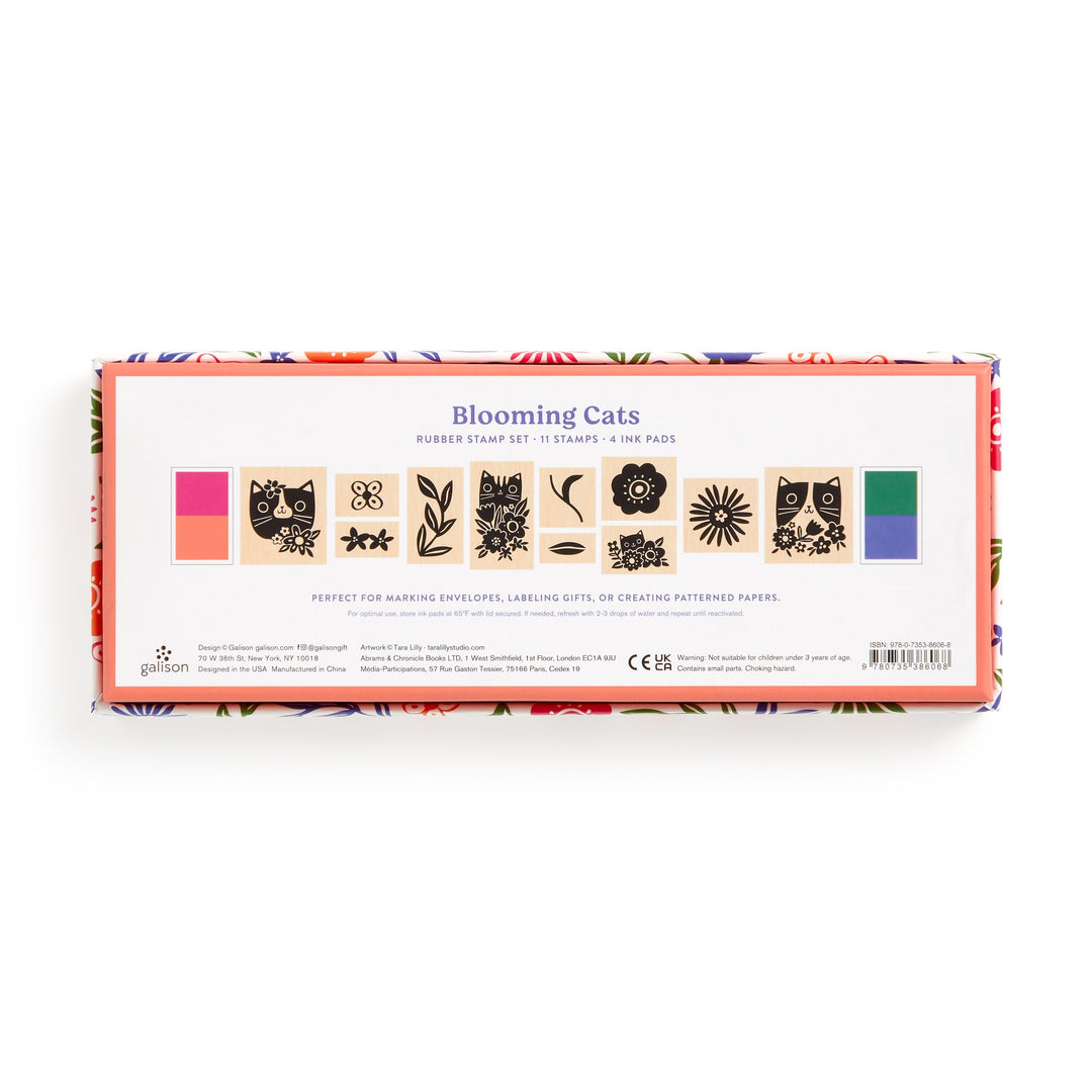 The Tara Lilly Blooming Cats Rubber Stamp Set includes 11 cat-themed stamps and 3 pink, green, and orange ink pads. Packaged in a floral-bordered box, it features botanical design elements.