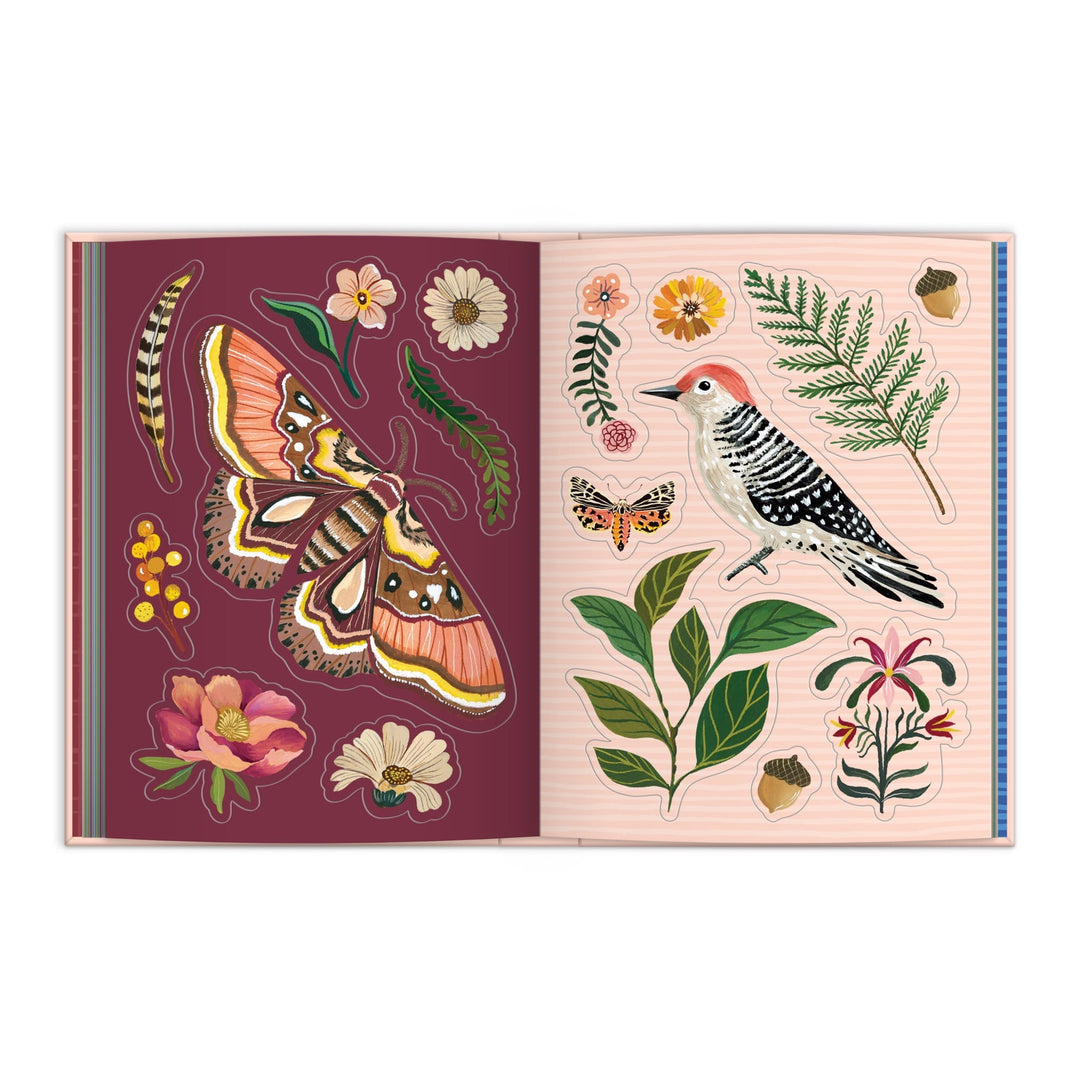 The Christine De Carvalho Art of the Forest 100 Page Sticker Book is open, revealing colorful wildlife stickers—a large moth, flowers, leaves, a caterpillar, a woodpecker, and a fern—across burgundy and light pink pages.