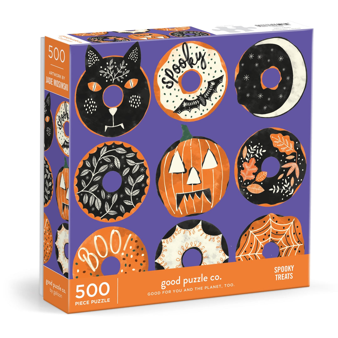 The Good Puzzle Co. Spooky Treats 500pc Puzzle by Laura Watkins features Halloween donuts, a cat, pumpkin, crescent moon, and festive designs in black, orange, and white on purple—a perfect fall activity.
