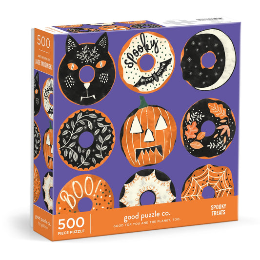 The Good Puzzle Co. Spooky Treats 500pc Puzzle by Laura Watkins features Halloween donuts, a cat, pumpkin, crescent moon, and festive designs in black, orange, and white on purple—a perfect fall activity.