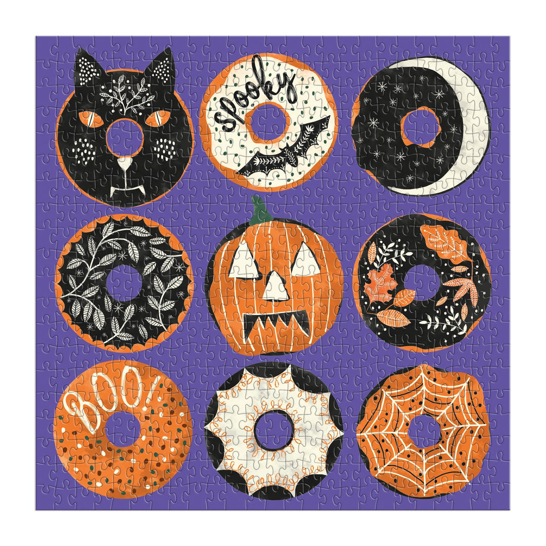 The Good Puzzle Co. Spooky Treats 500pc Puzzle by Laura Watkins features nine uniquely designed Halloween donuts on a purple background, making it the ideal festive challenge for fans of fun and spooky puzzles.