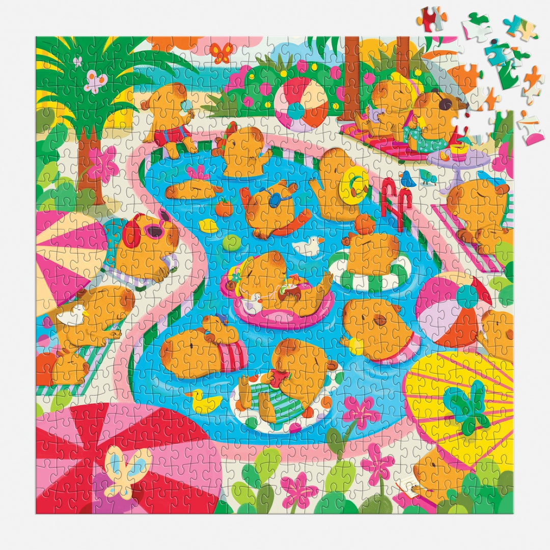 The Capybara Pool Day 500 Piece Family Puzzle by Valerie Nelson features charming cartoon capybaras relaxing by the pool, floating on floats, lounging on towels, and playing—perfect for family puzzle nights!.