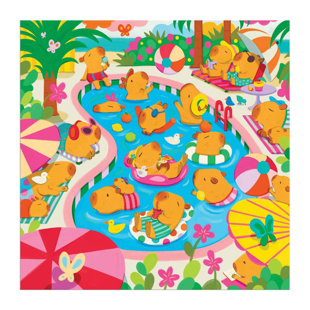 The Capybara Pool Day 500 Piece Family Puzzle by Valerie Nelson features colorful capybaras swimming, floating on pool rings, snacking, and relaxing under umbrellas among flowers, palm trees, and playful pool toys.