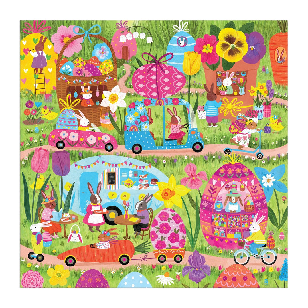 Jenny Miriam’s Hoppin' Around 500 Piece Family Puzzle features a vibrant spring scene with rabbit families driving cars, biking, and picnicking among flowers, eggs, and whimsical homes—perfect for family fun!.