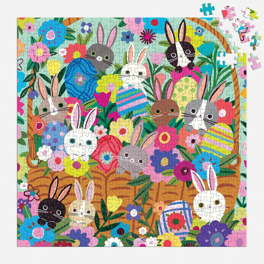 The Tara Lilly Blooming Bunnies 500 Piece Foil Family Puzzle features vibrant flowers, cartoon bunnies, and a basket of Easter eggs with scattered pieces for extra fun.